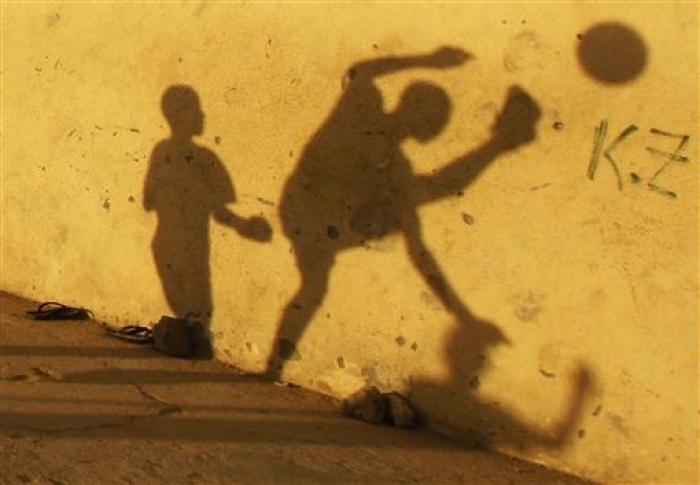 le-ombre-di-bambini-su-un-muro-mentre-giocano-a-pallone-in-una-strada-di-benguela
